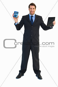 Smiling businessman with digital tablet and calculator