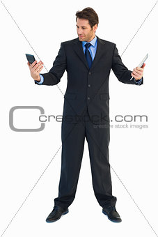 Businessman looking at his calculator and holding tablet pc