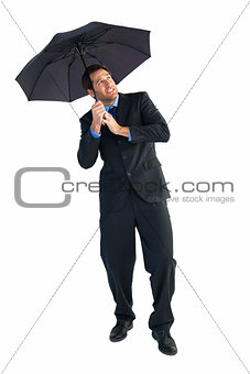 Businessman standing under black umbrella