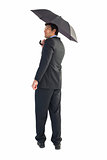 Businessman looking up while holding black umbrella