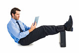 Businessman sitting using tablet with feet on his briefcase