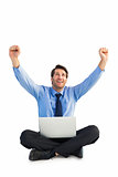 Businessman cheering with laptop sitting on floor