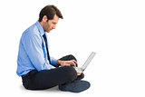 Businessman sitting on floor working on laptop
