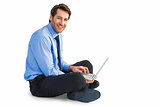 Smiling businessman sitting on floor working on laptop