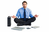 Man sitting in lotus pose with laptop, tablet and suitcase