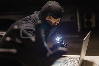 Robber looking at camera while making light with his phone