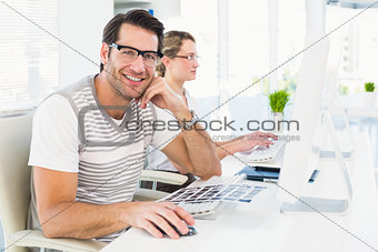 Man wearing glasses sitting at desk looking at camera