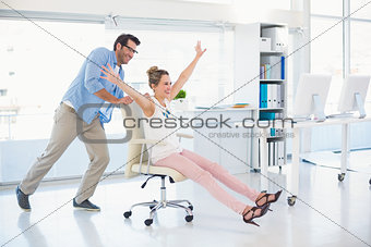 Smiling photo editors having fun with on a swivel chair