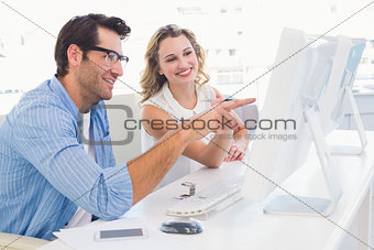 Creative designer talking to his colleague sitting at the desk