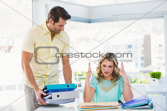 Tired creative businesswoman with stack of files on desk
