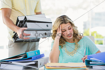 Stressed creative businesswoman with stack of files