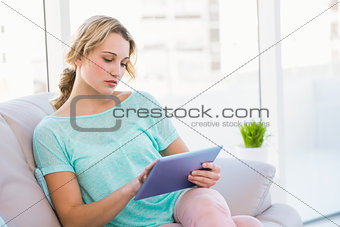 Blonde sitting on couch using tablet