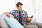 Happy man sitting on the couch sending a text message