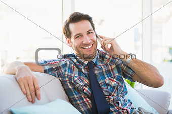 Cheerful man sitting on the couch making a phone call
