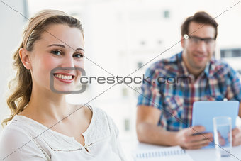 Smiling creative businesswoman with her colleague behind
