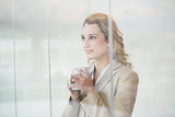 Pretty blonde holding cup of coffee through the window