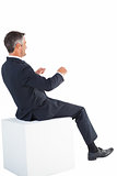 Smiling businessman sitting on a cube