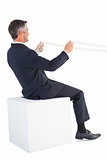 Businessman sitting on a cube and holding rope
