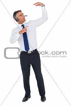 Smiling businessman with headphone pointing