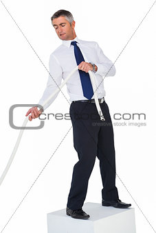 Businessman standing on a cube and pulling rope