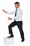 Businessman with one foot on a cube and arms out