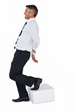 Businessman with one foot on cube and hands behind his back