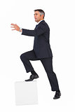 Businessman climbing on a cube with arms out