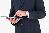 Mid section of a businessman touching tablet