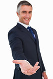 Smiling businessman in suit with arm out