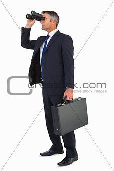 Businessman in suit looking through binoculars
