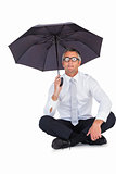 Businessman wearing glasses sheltering with umbrella