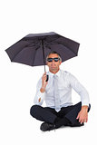 Businessman wearing sunglasses and sheltering with umbrella