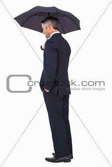 Businessman in suit standing under umbrella