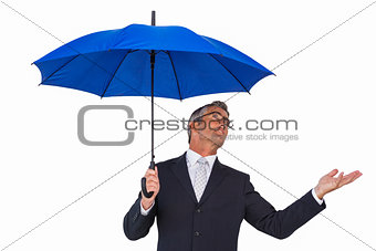 Businessman under blue umbrella with hand out