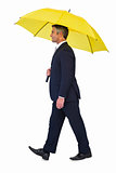 Businessman walking and holding yellow umbrella