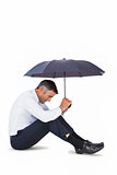 Businessman sitting and sheltering with umbrella