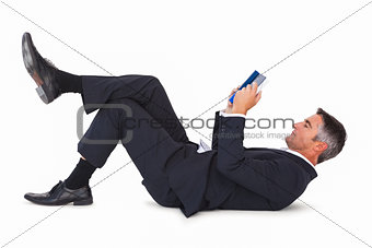 Relaxed businessman lying and reading book
