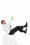 Businessman sitting and pulling a rope