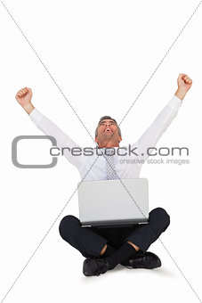 Happy businessman cheering and sitting with his laptop