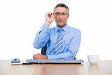 Businessman holding his glasses and using keyboard