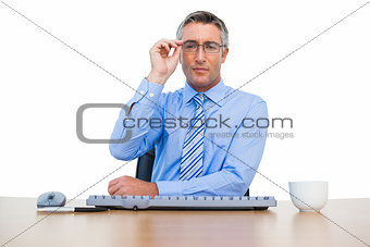 Businessman holding his glasses and using keyboard
