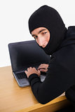 Burglar hacking a laptop and looking behind him