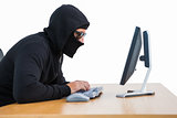 Burglar with sunglasses typing on keyboard