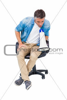 Man sitting on a office chair speaking on megaphone
