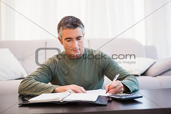 Man taking notes with calculator and notepad on the table