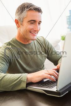 Smiling man with grey hair using laptop