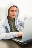 Smiling man in hood jacket using laptop