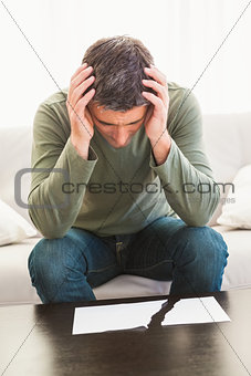 Sad man with hands on his head looking ripped paper