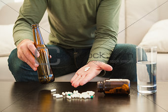 Man showing pills and holding beer bottle