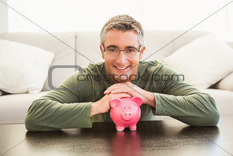 Smiling man with a pink piggy bank